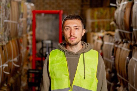 Téléchargez les photos : Portrait d'un homme sérieux en uniforme debout dans le couloir d'une usine de recyclage des déchets regardant la caméra - en image libre de droit