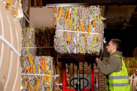 Téléchargez les photos : Un travailleur d'une station de traitement des déchets sort une grande boîte de choses dans un couloir sombre d'un centre de traitement des déchets - en image libre de droit