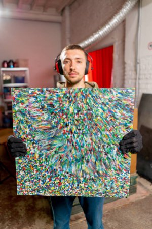 Téléchargez les photos : Un employé d'usine tient une peinture faite de bouchons de bouteilles en plastique déchiqueté dans une station de recyclage des déchets - en image libre de droit