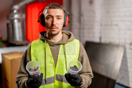 Photo for Portrait of a man in a uniform and headphones holding glasses with shredded plastic lids for recycling - Royalty Free Image