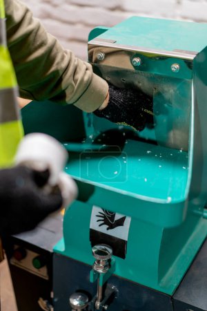 Téléchargez les photos : Gros plan des mains masculines dans des gants versant des bouchons en plastique dans un appareil de déchiquetage pour recyclage - en image libre de droit