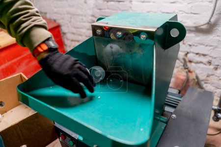 Foto de Primer plano de las manos masculinas en guantes vertiendo tapas de plástico en un aparato de trituración para el reciclaje - Imagen libre de derechos