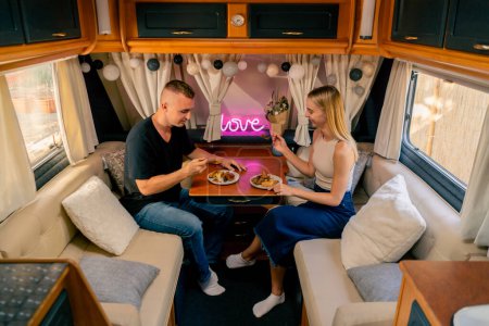 Photo for Couple in love together on a date in a mobile home sitting at the table and having dinner in a romantic setting - Royalty Free Image