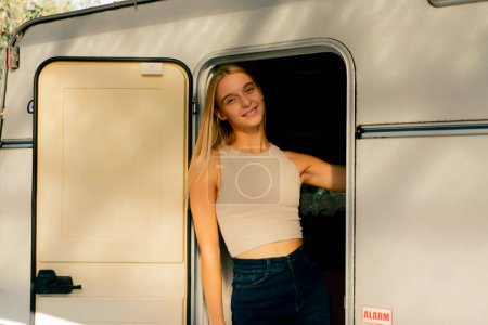 Téléchargez les photos : Une belle fille souriante sort ouvre les portes et quitte la maison sur roues tout en voyageant - en image libre de droit