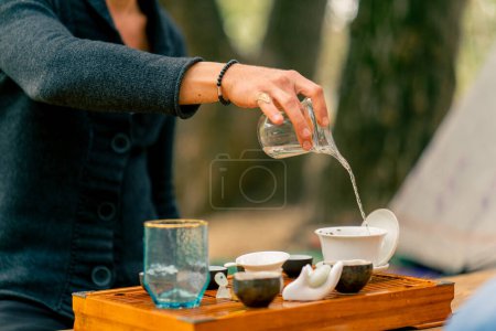 Téléchargez les photos : Une main d'homme verse de l'eau bouillante dans des bols en céramique pour faire du thé lors d'une masterclass cérémonie du thé - en image libre de droit