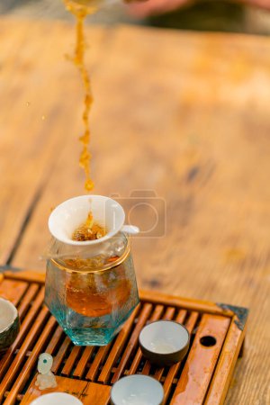 Téléchargez les photos : Gros plan sur le thé chinois naturel infusé versé dans une petite théière en verre lors d'une cérémonie traditionnelle du thé - en image libre de droit
