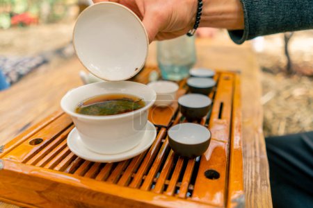 Téléchargez les photos : Gros plan des feuilles de thé chinois naturel brassées dans un bol en céramique spécial avec un couvercle pendant la cérémonie - en image libre de droit