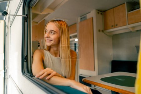 Photo for A beautiful girl rides in a trailer on a trip looks out the open window and smiles sincerely from the beautiful views along the way - Royalty Free Image