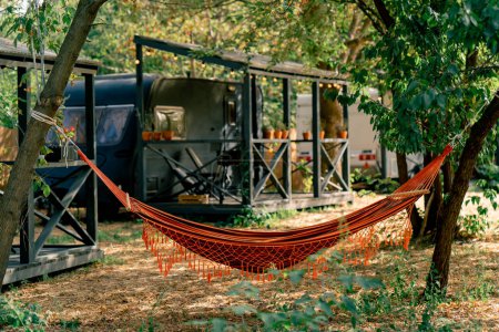 Téléchargez les photos : Un hamac attaché aux arbres sur le territoire des campings avec camping-cars pour le repos et la détente des voyageurs - en image libre de droit