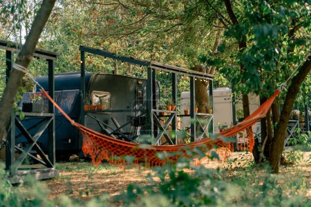 Foto de Una hamaca atada a los árboles en el territorio de campings con autocaravanas para el descanso y la relajación de los viajeros - Imagen libre de derechos