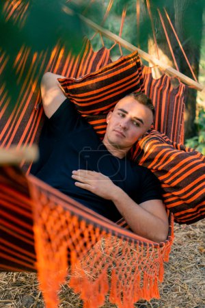 Foto de Un hombre miente relajado en una hamaca que descansa y que relaja mientras que vacationing en glamping en el campo - Imagen libre de derechos