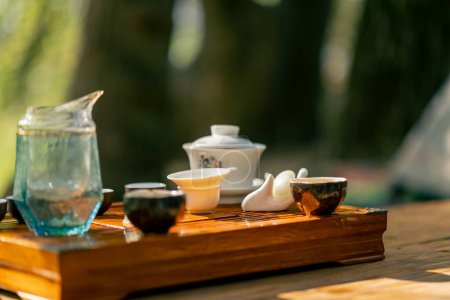 Photo for Ceramic bowls and a small glass teapot are displayed on a wooden table on the street in the early morning - Royalty Free Image