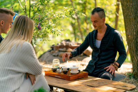 Téléchargez les photos : Un couple amoureux suit de près le processus d'une cérémonie du thé par un maître de thé masculin qui brasse des herbes naturelles - en image libre de droit