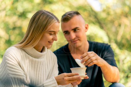 Foto de Primer plano de una pareja sonriente enamorada relajándose juntos y degustando té natural durante una ceremonia de té en la naturaleza - Imagen libre de derechos