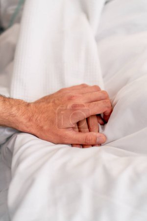 Téléchargez les photos : Gros plan de la main d'un médecin tenant la main d'une patiente sur un lit dans un service hospitalier pour un soutien moral - en image libre de droit