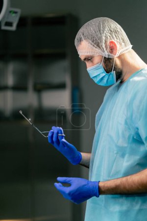 Foto de Primer plano de un médico cirujano con un uniforme especial que prepara los instrumentos antes de la cirugía en un quirófano - Imagen libre de derechos