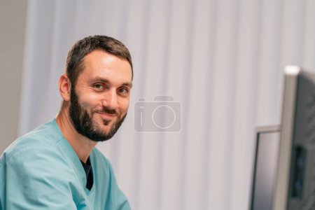 Photo for A smiling and concentrated radiologist sits at his desk and diagnoses patients on a magnetic resonance imaging machine - Royalty Free Image