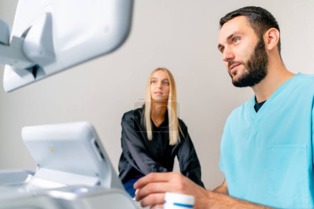 Photo for A girl patient sits on a gurney in the ultrasound diagnostic room after the procedure and listens carefully to a doctor - Royalty Free Image