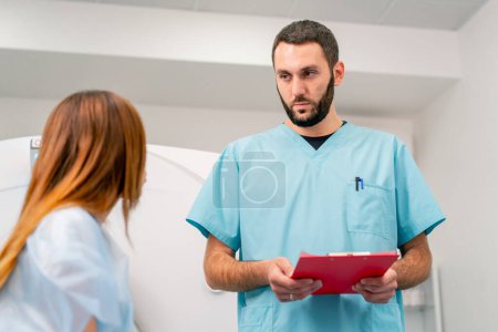 Téléchargez les photos : Gros plan d'un radiologue qui consulte une patiente avant de subir un diagnostic à l'aide d'une machine d'IRM dans un centre médical - en image libre de droit