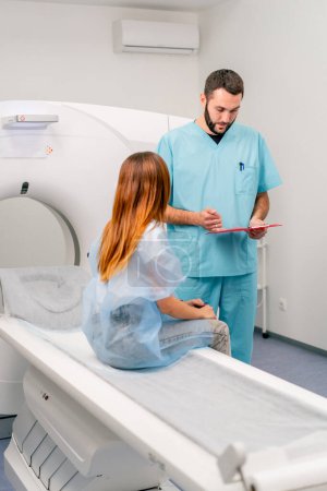 Foto de Un radiólogo consulta a una paciente antes de someterse a un diagnóstico utilizando una máquina de resonancia magnética en un centro médico - Imagen libre de derechos