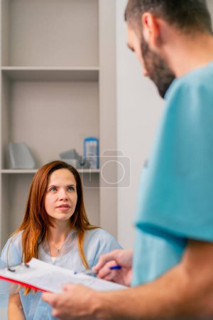 Foto de Primer plano de una paciente que describe quejas sobre su condición y bienestar a un radiólogo antes de examinarla con una resonancia magnética - Imagen libre de derechos