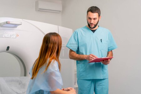 Photo for A radiologist describes to a patient the results of her examination after diagnosis using an MRI machine - Royalty Free Image