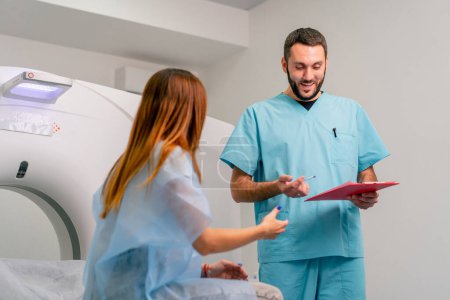 Téléchargez les photos : Un radiologue décrit à une patiente les résultats de son examen après diagnostic à l'aide d'un appareil d'IRM - en image libre de droit