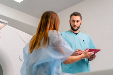 Photo for Close-up shot of a radiologist carefully recording the patient's complaints and symptoms before examining her on a computed tomography scan - Royalty Free Image