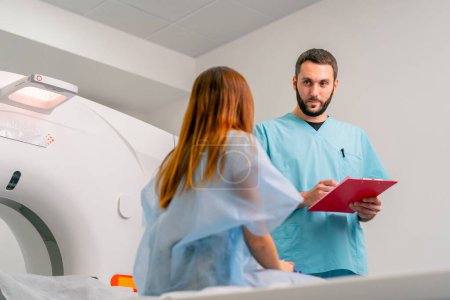 Photo for Close-up shot of a radiologist carefully recording the patient's complaints and symptoms before examining her on a computed tomography scan - Royalty Free Image