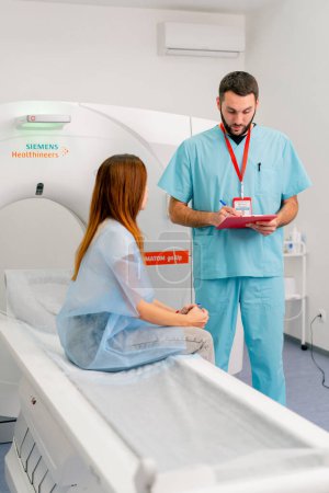 Téléchargez les photos : Un radiologue décrit à la patiente les résultats de son examen après diagnostic à l'aide d'un appareil d'IRM - en image libre de droit