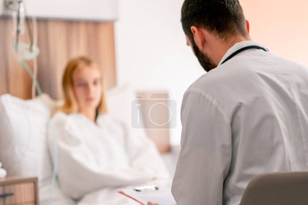 Téléchargez les photos : Une fille malade se trouve dans la chambre d'hôpital et tient sa poitrine avec sa main et une toux près du médecin - en image libre de droit