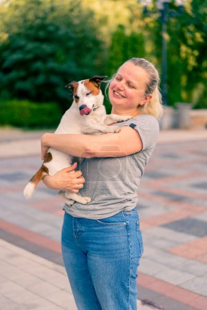 Téléchargez les photos : Portrait d'une femme tenant son petit chien de la race Jack Russell terrier soins animaux amitié - en image libre de droit