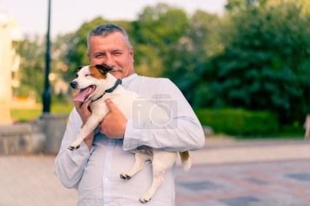 Foto de Retrato de un hombre barbudo adulto sosteniendo su pequeño perro de la raza Jack Russell Terrier cuidando animales amistad - Imagen libre de derechos