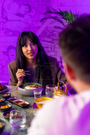 Foto de Retrato de una chica disfrutando de la cocina tradicional coreana con palillos en un restaurante con novio en una cita - Imagen libre de derechos