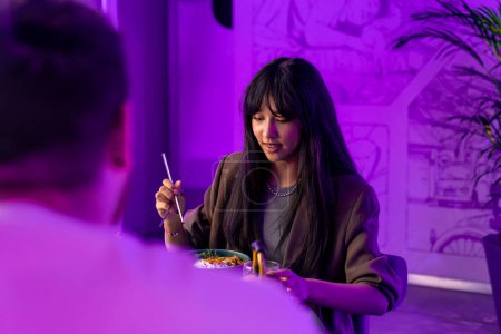 Photo for Portrait of a girl enjoying traditional Korean cuisine with chopsticks in a restaurant with boyfriend on a date - Royalty Free Image
