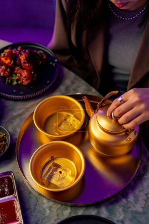 Photo for Close-up serving gold teapot and cup with ice traditional Korean soft drink makoli in restaurant - Royalty Free Image
