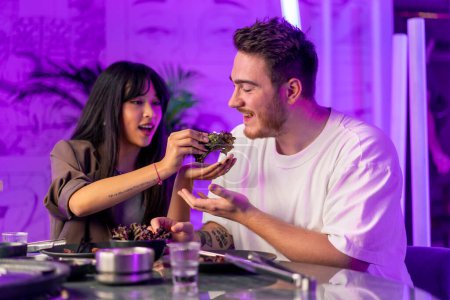 Téléchargez les photos : Couple en amour coréen grill restaurant goût divers plats traditionnels se nourrissent mutuellement concept alimentaire - en image libre de droit