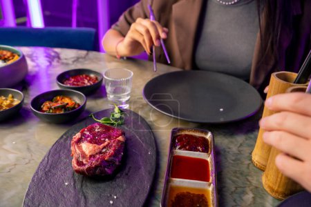Téléchargez les photos : Un couple amoureux dans un restaurant coréen avec un gril et une hotte au-dessus de la table goûte une variété de plats traditionnels avec des baguettes concept alimentaire - en image libre de droit