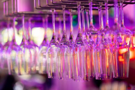 Foto de Vasos de vidrio en el mostrador de bar en neón luz rosa en la celebración del bar restaurante bebidas alcohólicas - Imagen libre de derechos