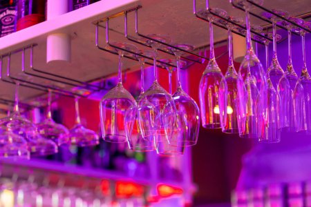 Téléchargez les photos : Verres en verre sur le comptoir du bar en néon rose lumière dans le restaurant bar célébration boissons alcoolisées - en image libre de droit