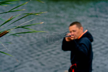Foto de Retrato Pescador con caña de pescar spinning y herramientas profesionales sentado en la orilla del río pesca deportiva - Imagen libre de derechos