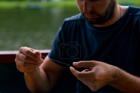 Foto de Un joven encadena una línea de pesca o una mosca en el gancho para el método de estilo libre alimentador de pesca - Imagen libre de derechos