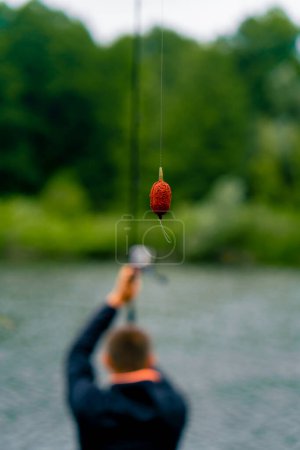 Foto de Pescador lanza una caña de pescar o caña de spinning en el agua mientras está sentado en la orilla del río en el muelle Tire de peces fuera de la pesca deportiva lago - Imagen libre de derechos