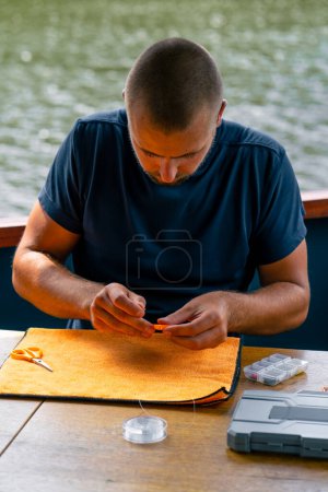 Foto de Un joven encadena una línea de pesca o una mosca en el gancho para el método de estilo libre alimentador de pesca - Imagen libre de derechos