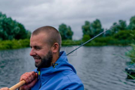 Téléchargez les photos : Portrait Pêcheur avec canne à pêche filature et outils professionnels assis sur la rive de la rivière pêche sportive - en image libre de droit