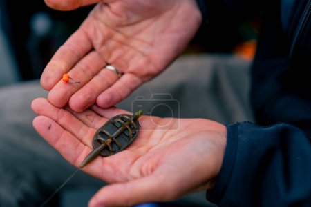 Téléchargez les photos : Gros plan main de pêcheur mâle enfilant un appât sur le crochet d'une canne à pêche pour attraper des poissons de rivière - en image libre de droit