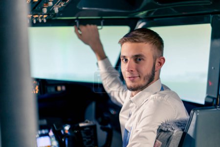 Foto de Retrato del capitán sonriente del avión en uniforme preparando vuelo en cabina del simulador de vuelo - Imagen libre de derechos