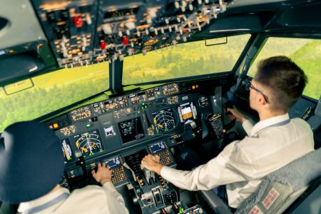 Photo for Rear view of pilots in the cockpit of an airplane during flight control in turbulence zone flight simulator - Royalty Free Image