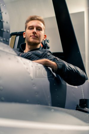 Téléchargez les photos : Un jeune homme assis dans un simulateur de vol d'un avion militaire avant le début d'un divertissement de vol virtuel - en image libre de droit