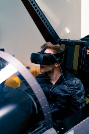 Téléchargez les photos : Garçon assis dans le simulateur de vol avion militaire portant des lunettes de réalité virtuelle pendant le divertissement de vol - en image libre de droit